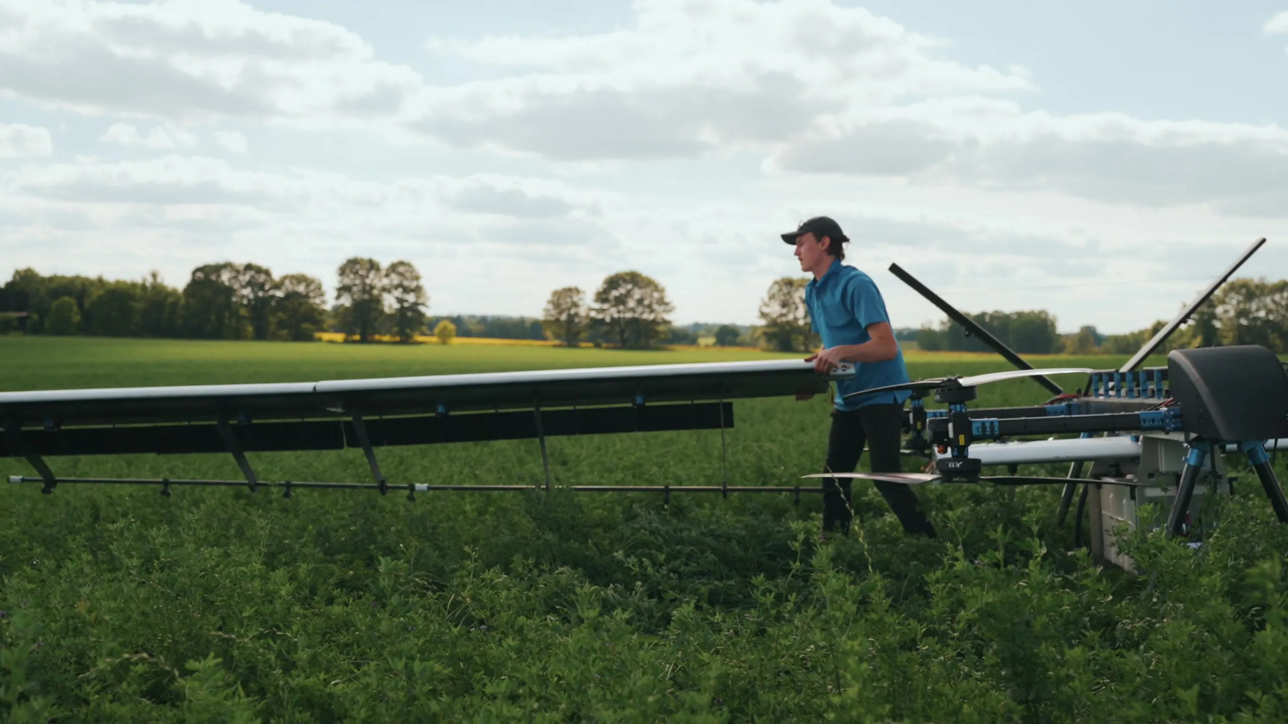 An operator standing beside the U9 Spray in a field, reaching the wing at about shoulder height.
